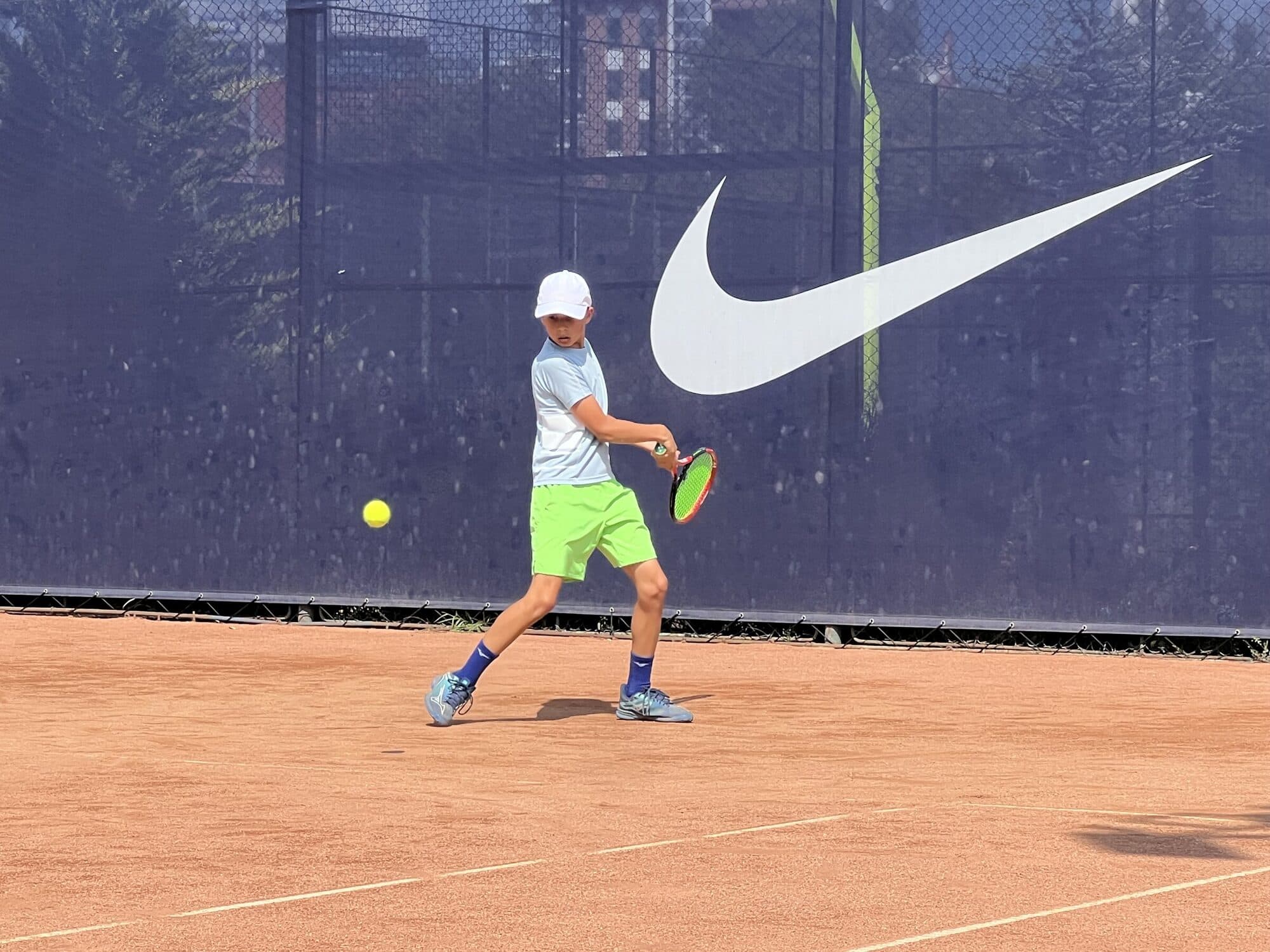 Ioan Ianculescu lovind un forehand pe terenul de zgură, cu mingea în aer